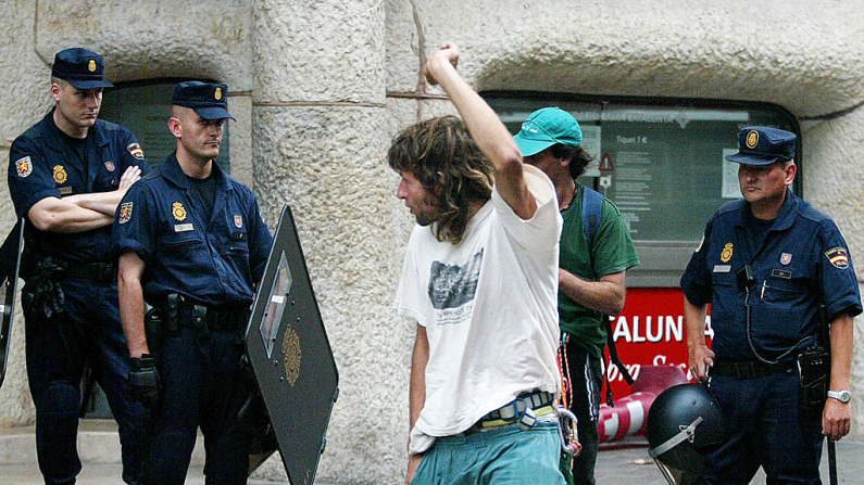 Las fuerzas de seguridad observan a dos okupas que abandonan el lugar tras haberse refugiado en la fachada de La Pedrera, emblemático edificio modernista del arquitecto Antoni Gaudí, de Barcelona, el 04 de agosto de 2004 para protestar contra el desalojo. AFP PHOTO/CESAR RANGEL 