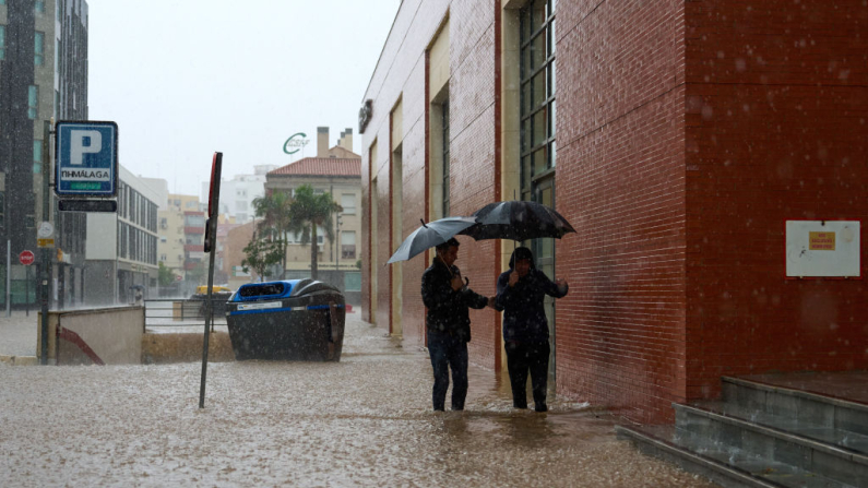 Dos hombres intentan refugiarse durante una fuerte tormenta cerca del barrio de El Perchel el 13 de noviembre de 2024 en Málaga, España. (Angel Martinez/Getty Images)