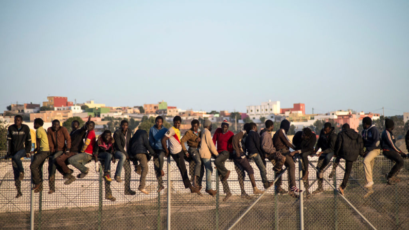 Los inmigrantes que intentan llegar a Melilla, territorio español del norte de África, se encuentran en la frontera el 22 de octubre de 2014, tras un asalto matutino en la frontera en un intento de cruzar a España. El jefe de la delegación del gobierno español en el territorio, Abdelmalik El Barkani, dijo que el número de intentos de inmigrantes que buscan escalar la valla de siete metros (23 pies) de triple capa que separa Melilla de Marruecos ha aumentado en 2014. (Jesús Blasco de Avellaneda /AFP vía Getty Images)