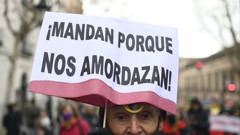 Un manifestante sostiene una pancarta con la leyenda "¡Ellos mandan porque nos amordazan!" durante una protesta contra la controvertida ley de seguridad conocida como "Ley Mordaza" en Madrid, el 13 de febrero de 2022. La ley de seguridad ciudadana española de 2015 fue conocida como "Ley Mordaza" por su ofensiva contra la libertad de expresión y las amplias facultades que otorgaba a la policía. (Oscar del Pozo / AFP vía Getty Images)