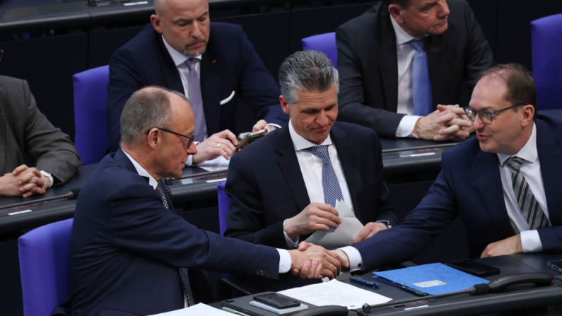  El canciller designado y líder de los Demócratas Cristianos Alemanes (CDU) Friedrich Merz (izquierda) estrecha la mano de su colega Alexander Dobrindt, de los Demócratas Cristianos Bávaros (CSU), en el Bundestag tras una votación exitosa sobre los cambios en la Ley Fundamental de Alemania el 18 de marzo de 2025 en Berlín, Alemania. Los cambios facilitarán la flexibilización de las restricciones sobre los límites de deuda del gobierno federal, así como el gasto en defensa a gran escala. (Sean Gallup/Getty Images)