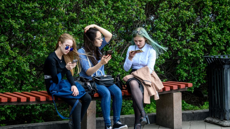 Unas chicas usan sus celulares sentadas en un banco el 24 de mayo de 2018. Imagen de archivo. (Mladen Antonov/ AFP vía Getty Images)