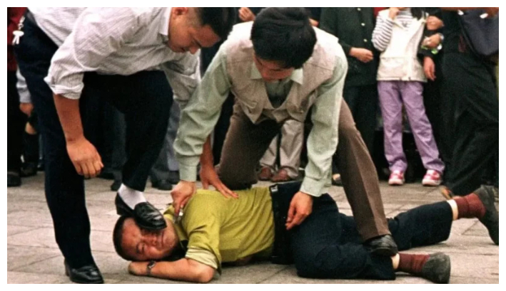 La policía china arresta a un practicante de Falun Gong en la Plaza de Tiananmen en Beijing el 1 de octubre de 2000. (Chien-min Chung/AP Photo)