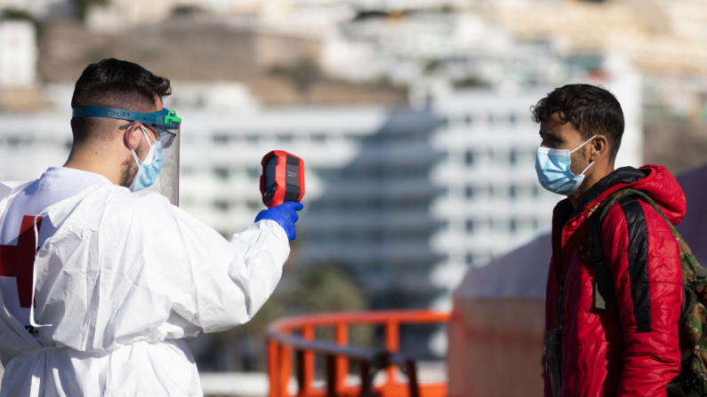 A un joven se le toma la temperatura para detectar síntomas de coronavirus tras desembarcar de un barco de la Guardia Costera española tras llegar al puerto de Arguineguín el 5 de diciembre de 2020 en Arguineguín, Gran Canaria, España. Dan Kitwood/Getty Images)