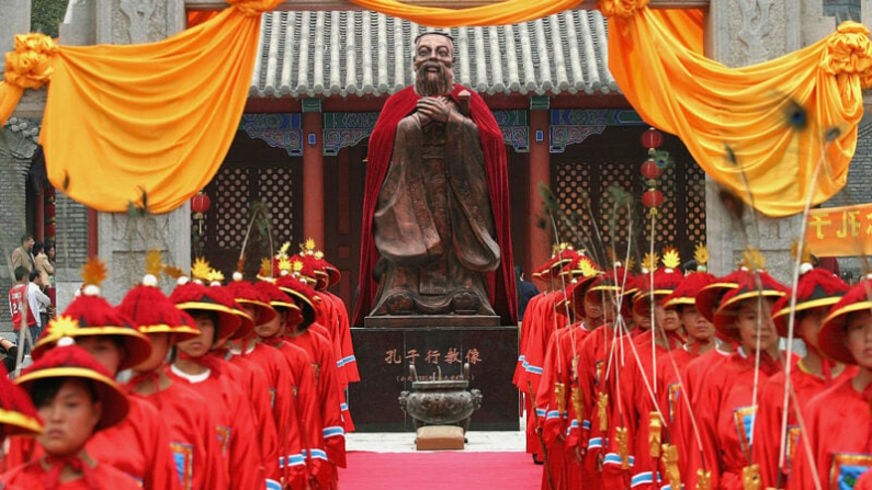 Changchun, China: estudiantes vestidos con ropas antiguas frente a una estatua de Confucio (551-479 a. C.). Después de que el Partido Comunista Chino destruyera la antigua cultura y sus valores y los sustituyera por su propia teoría de lucha en diversos movimientos antes y durante la Revolución Cultural, ahora se esfuerza por ponerse el manto de Confucio para difundir la ideología del PCCh en Occidente. Foto: China Fotos/Getty Images
