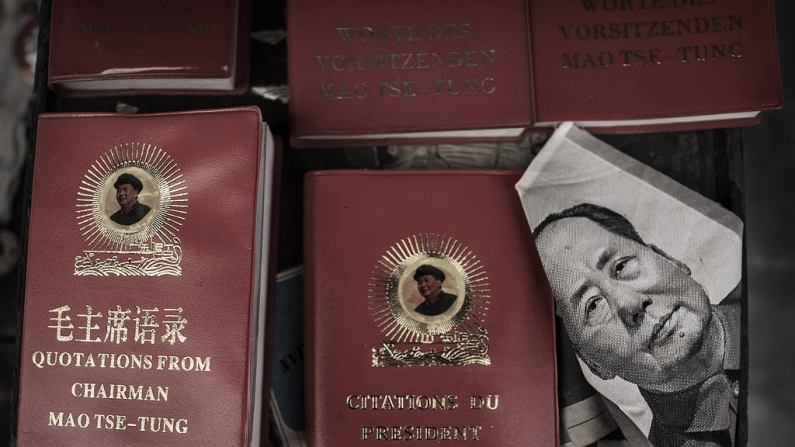 Un retrato del difunto dictador chino Mao Zedong junto a ejemplares de su famoso "Libro Rojo" en un mercado el 7 de septiembre de 2014 en Pekín, China. La ideología de Mao, responsable de la muerte de un estimado de 80 millones de chinos, integra la «cultura china» que se difunde en las instituciones culturales asentadas en universidades españolas. (Foto de Kevin Frayer/Getty Images)