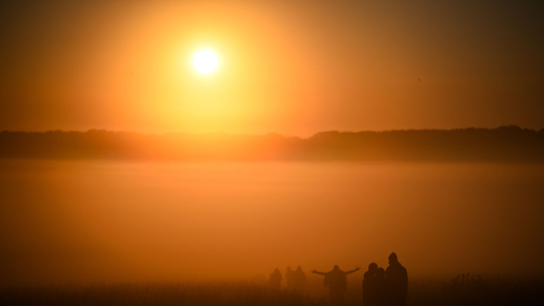 Visitantes caminan hacia el amanecer en Stonehenge, el 21 de junio de 2024 en Wiltshire, Inglaterra. En el día más largo del año en el hemisferio norte, el Sol sale en perfecta alineación con la Piedra del Talón y la Piedra del Altar del círculo de Stonehenge, de 5000 años de antigüedad. (Finnbarr Webster/Getty Images)