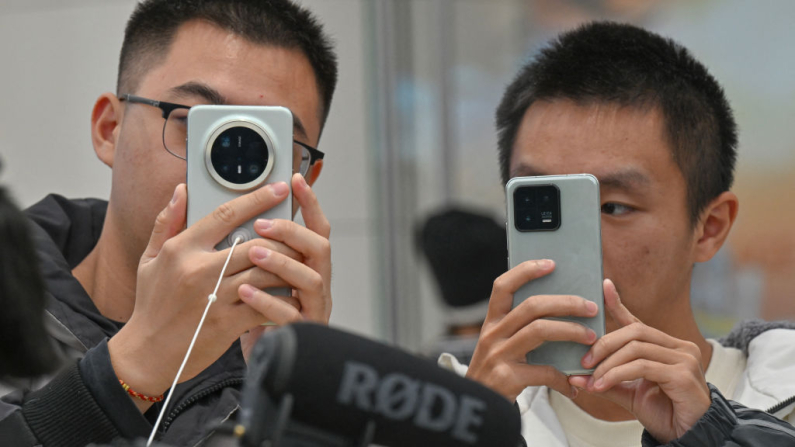 Personas revisan un teléfono móvil de Huawei en una tienda Huawei en la zona comercial Wangfujing de Pekín el 26 de noviembre de 2024. (Adek Berry/AFP vía Getty Images)