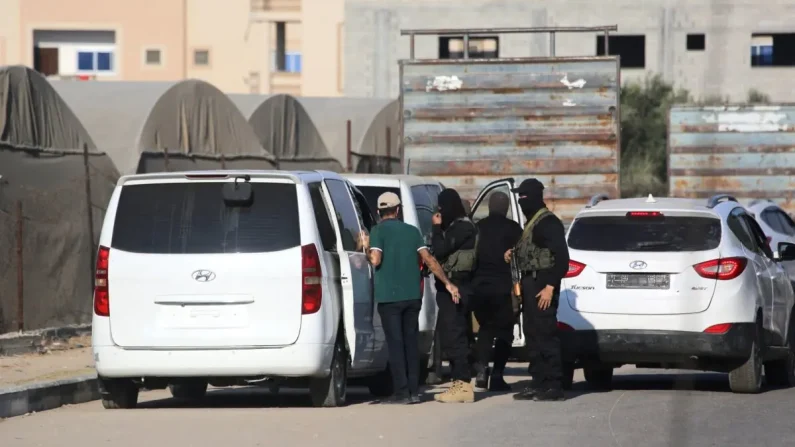 Miembros del ala militar de Hamás, las Brigadas Al-Qassam, hacen guardia junto a vehículos que transportan rehenes israelíes liberados en una carretera principal de Deir al-Balah, en el centro de la Franja de Gaza, el 13 de octubre de 2025. Bashar Taleb/AFP vía Getty Images.
