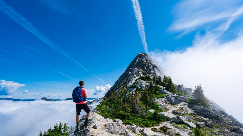 Un hombre observa la cumbre de una montaña desde las alturas con un paisaje montañoso. NZKGB. Pixabay