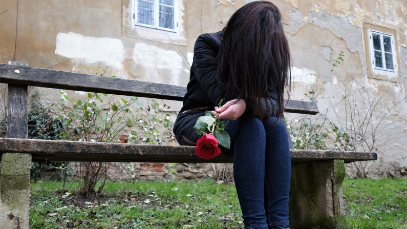 Una mujer sentada en un banco se cubre el rostro con su mano. Goran H. Pixabay