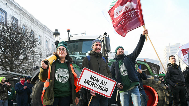 Manifestantes portan pancartas con la leyenda "No al Mercosur" y banderas del principal sindicato agrícola francés, FNSEA (Federación Nacional de Sindicatos de Explotantes Agrícolas) y de Jóvenes Agricultores (JA), cerca del Parlamento Europeo en la Plaza de Luxemburgo, el 18 de diciembre de 2025. (NICOLAS TUCAT / AFP vía Getty Images)